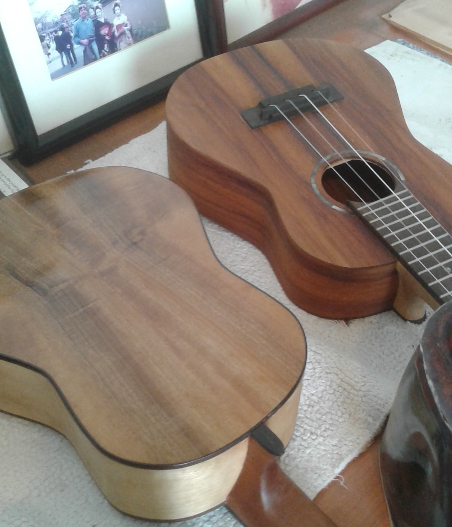 Nearly completed Koa ukulele on a glass table, with three holidays pies in the background